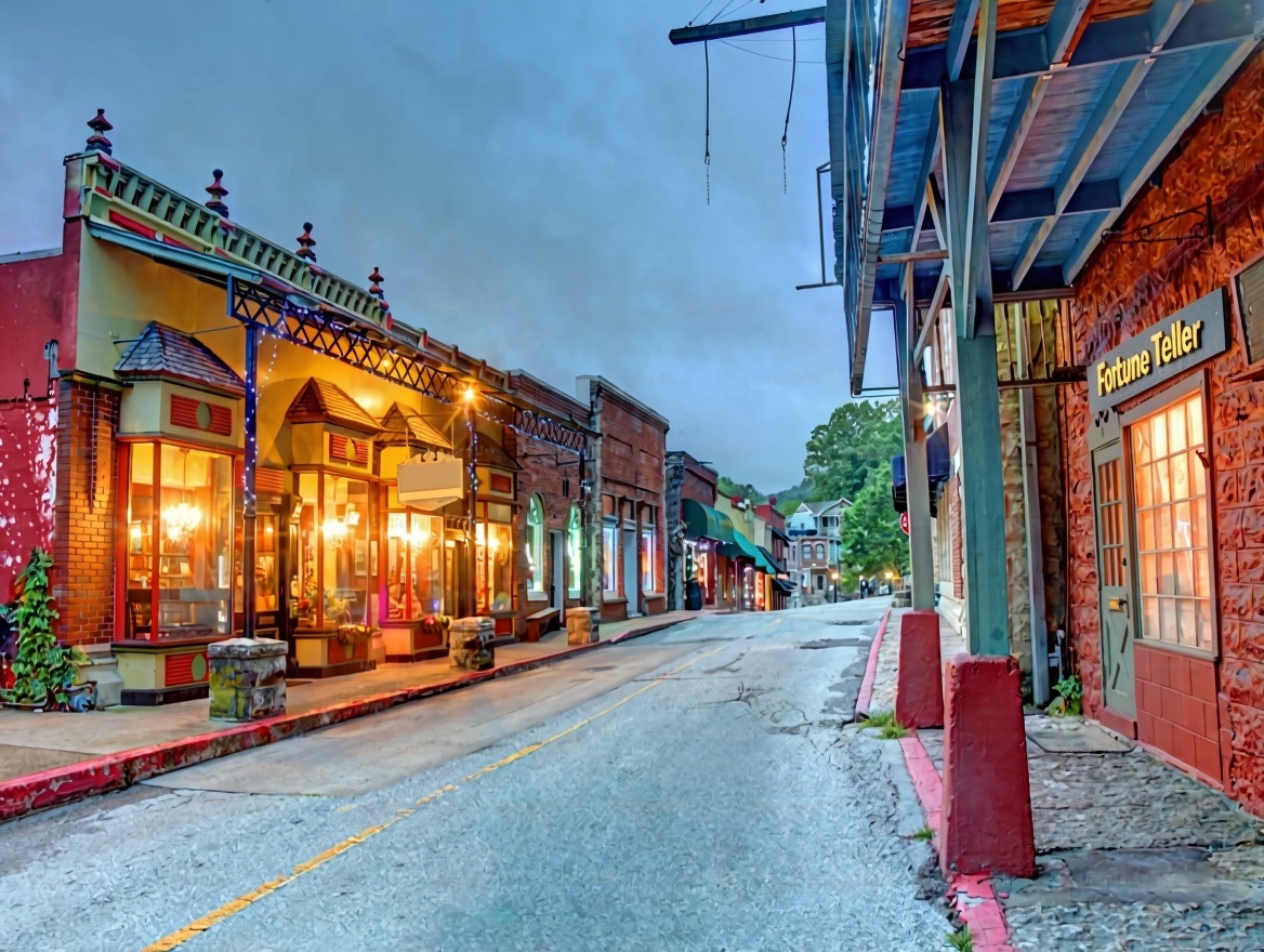 An evening street of Victorian storefronts with a lit Fortune Teller sign